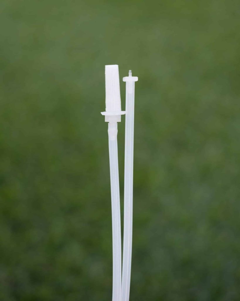 Two clear plastic drinking straws, one featuring a built-in cleaning brush, stand upright against a blurred green background—perfect for import placeholder,1139 refreshment needs.
