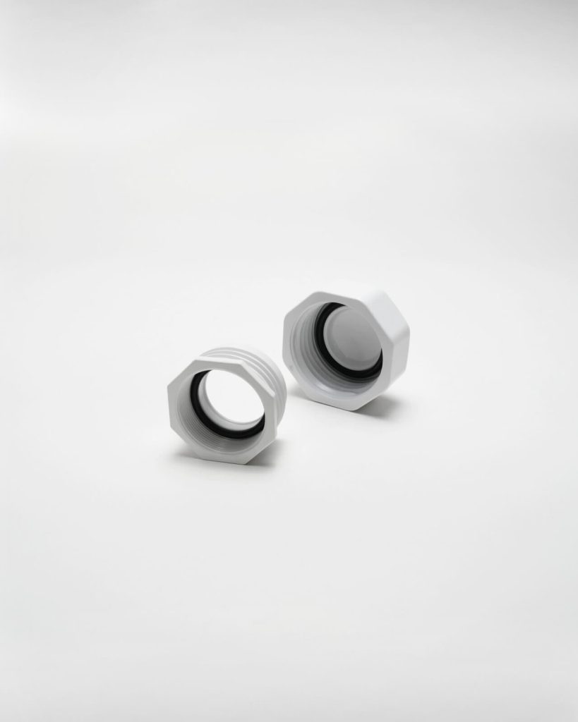 Two white hexagonal plastic nuts with inner threading, serving as a placeholder for 1130, are placed on a plain light background—one standing upright and the other lying on its side.