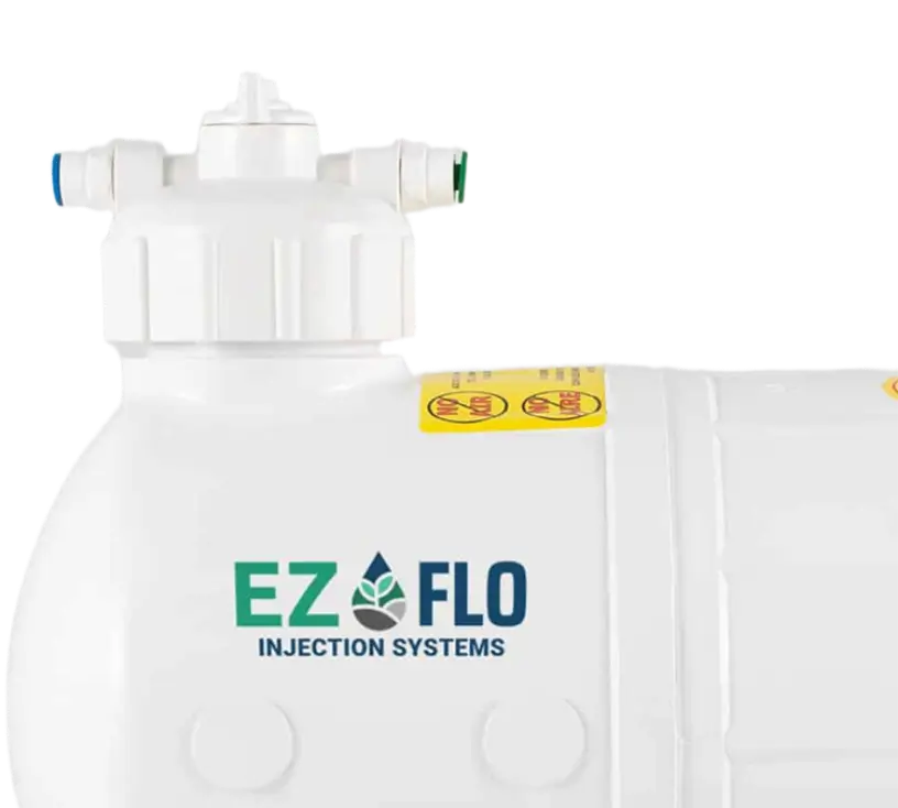Close-up of a white EZ-FLO Injection Systems device with labeled ports and warning stickers on the top and side.