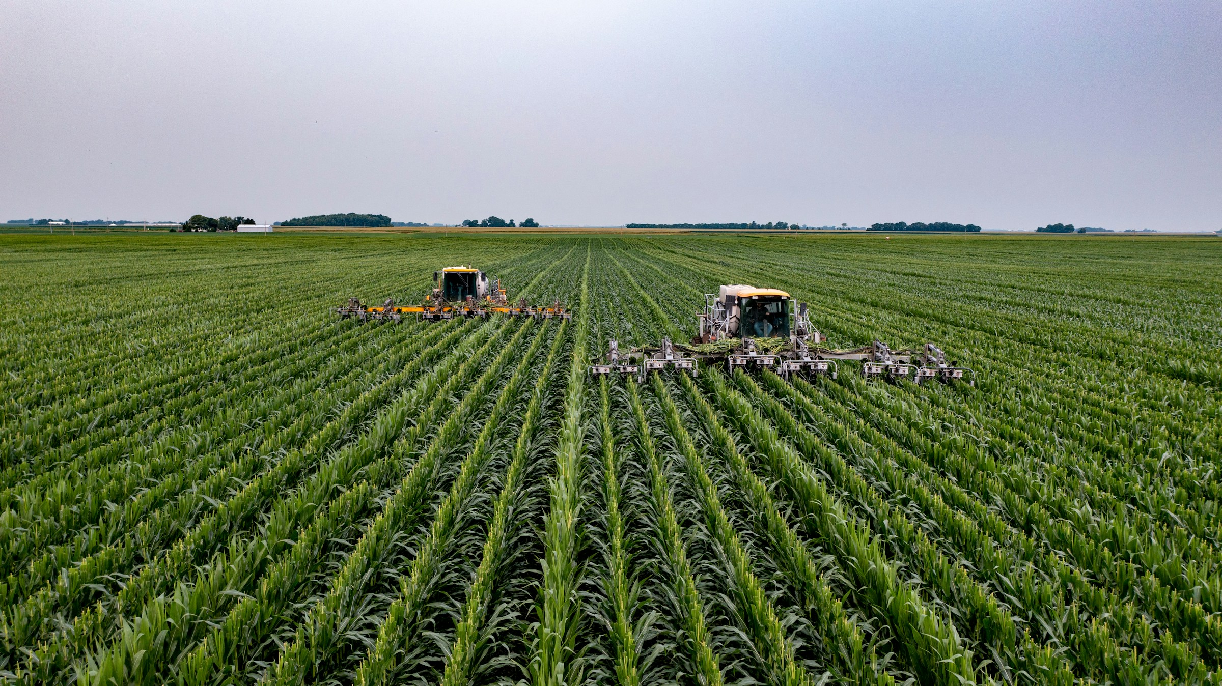 Two tractors engaged in E-Agriculture by working in a corn field.